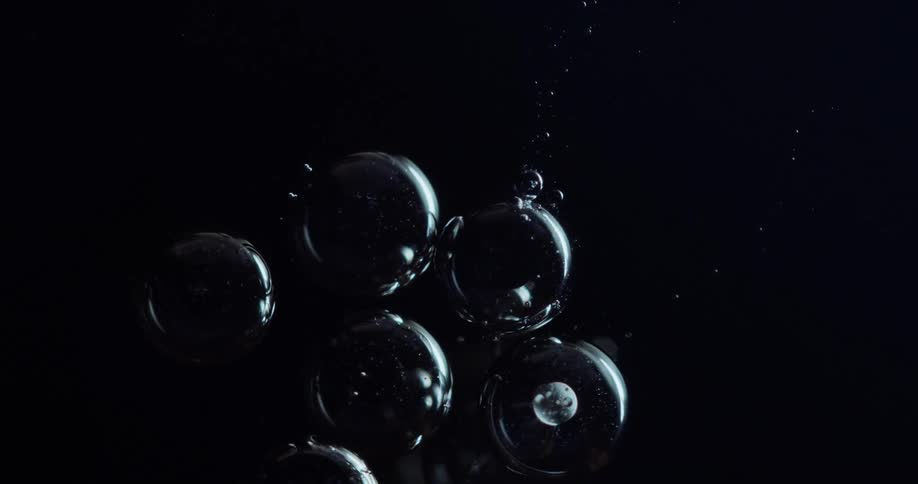 Moving air bubbles in an abstract liquid against a black background