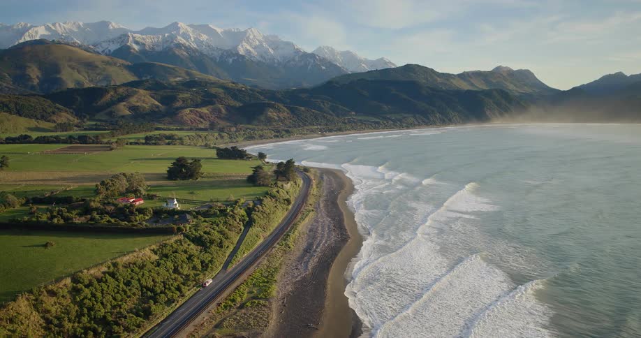 Aerial shot of a coastal highway with distant snowy mountains