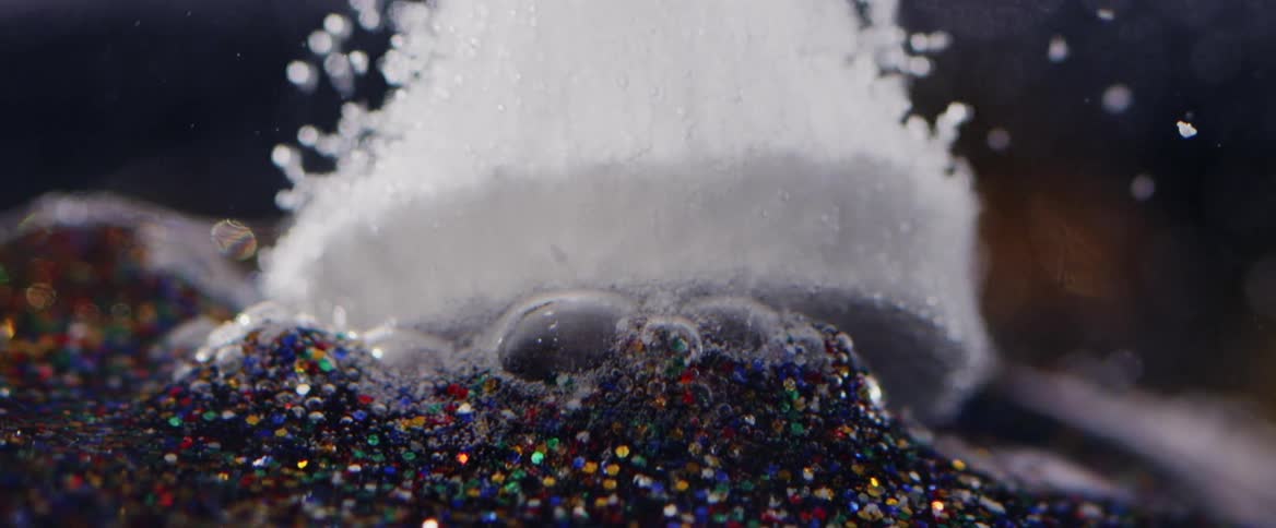 White pieces and bubbles rise from mass of small bits of colored sea glass