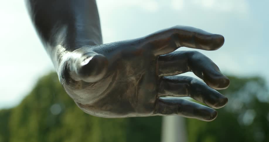 Close up of a sculpted hand connected to an arm outdoors during a bright sunny day