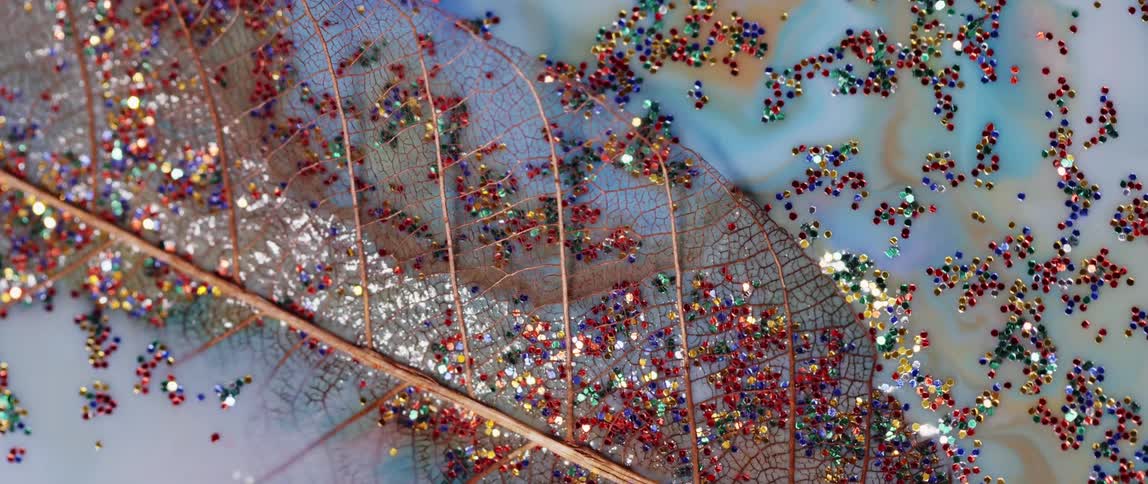 A gold leaf drowns in white liquid filled with colorful glitter