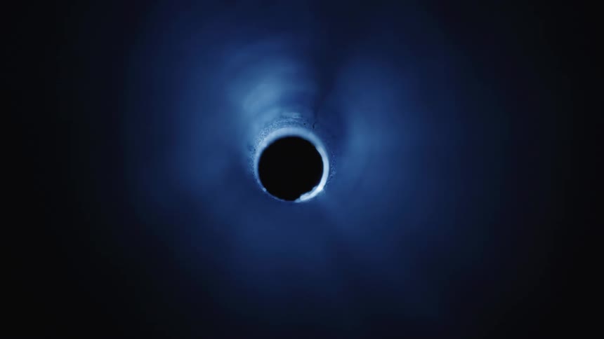 A black hole in the dark being illuminated by a small blue light