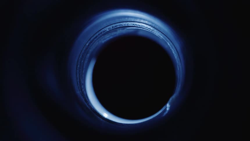A hole in a blue bottle cap that turns dark when a shadow passes through