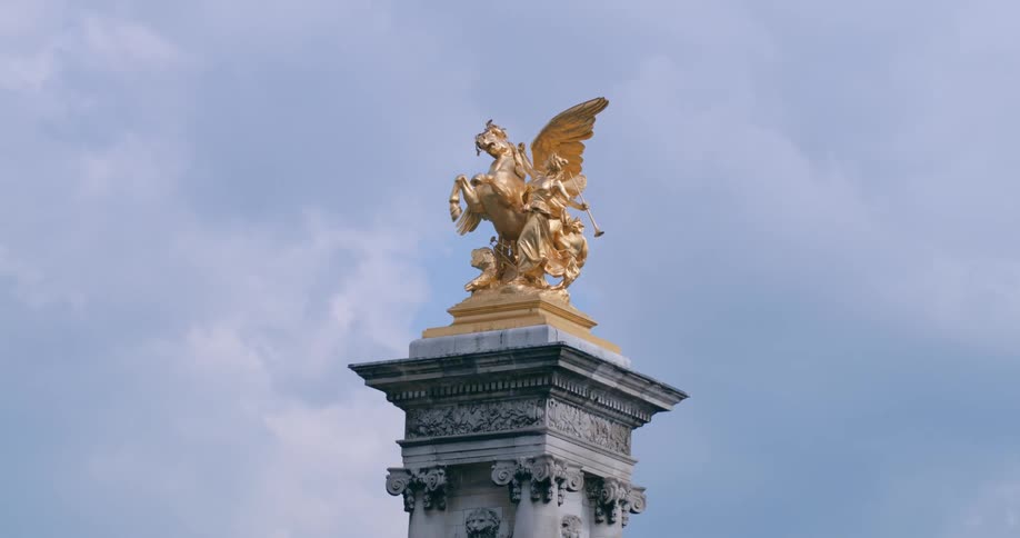 A golden statue of a woman and a horse with wings on a monument