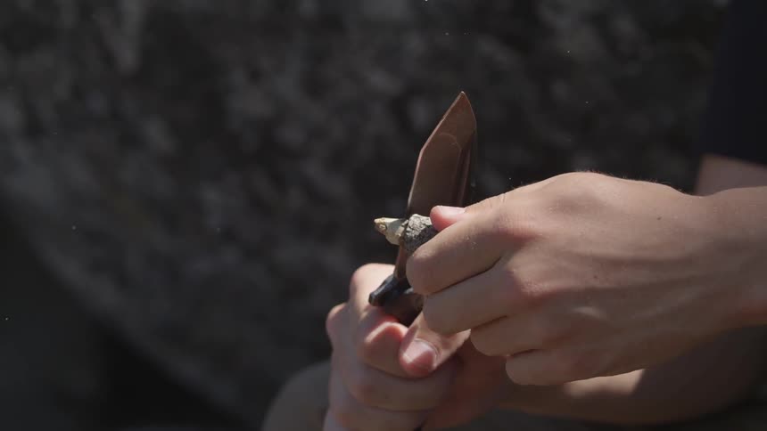 A man is sharpening a stick with a knife