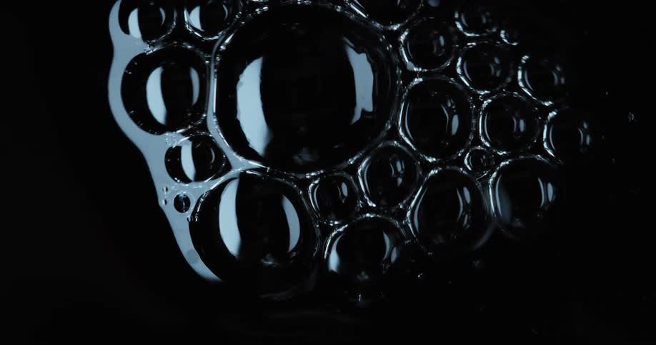 Abstract liquid bubbles bursting and colliding with each other against a black background
