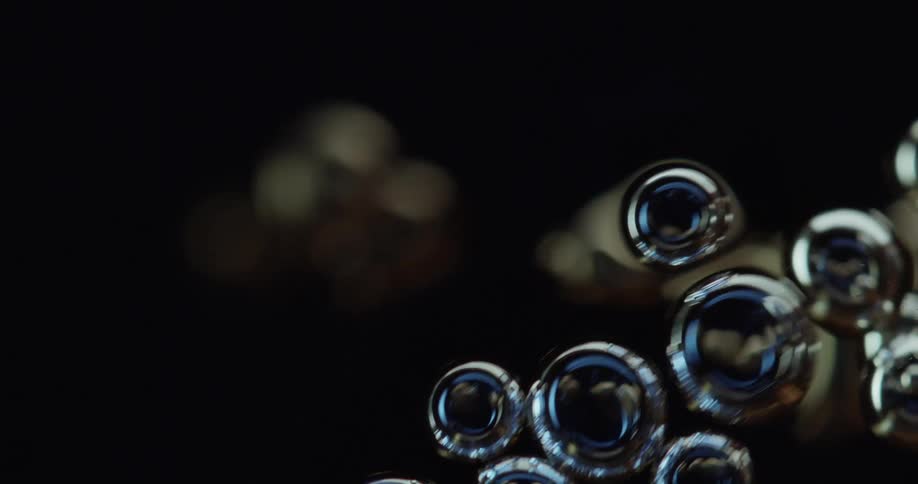 Light shines on clear spheres in the darkness as they multiply and float