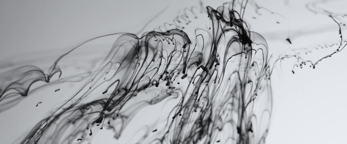 Streaks of black liquid move through water in slow motion