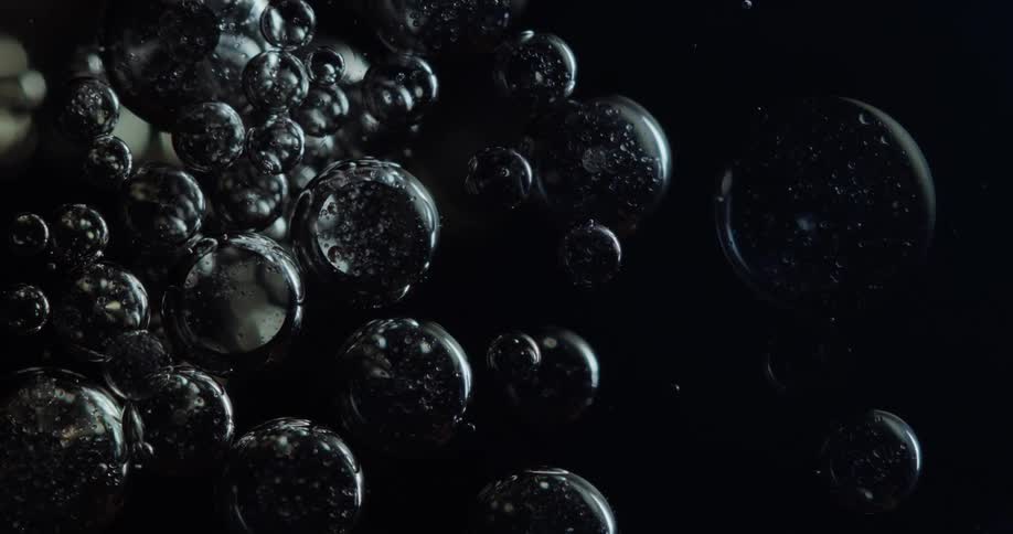 Light shines on bubbles as they float in the darkness