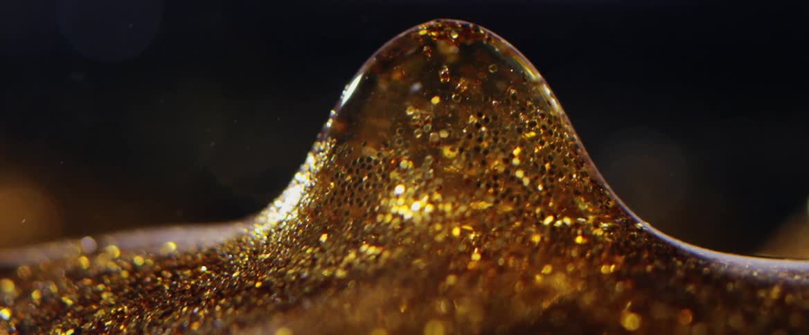 A glistening amber mound sparkles as it rises and an orb flies into the air from within