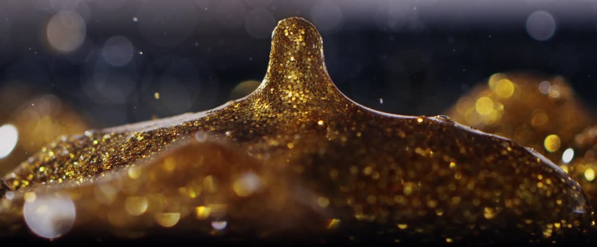 Gold glitter in a small lump as as drop of it slowly moves upward