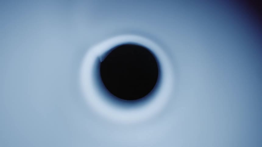 A dark circle lit up with bright lights around it and behind it like an eclipse