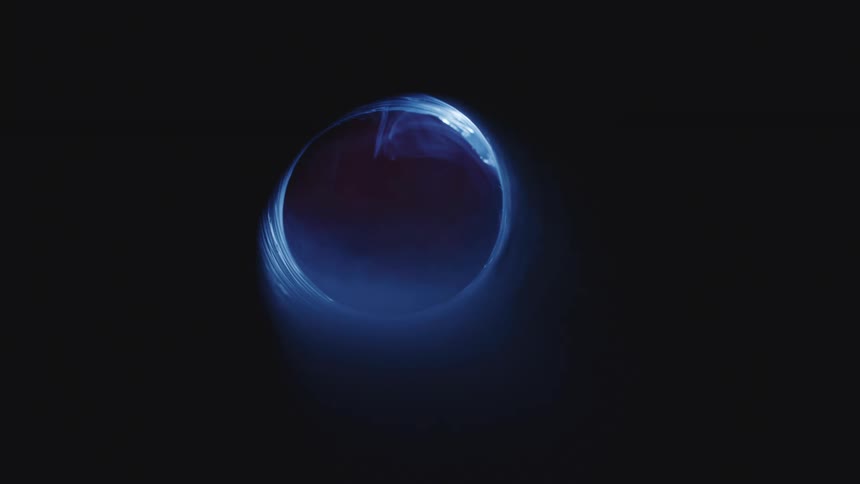 Blue light shines through a ring filled with whisps of smoke
