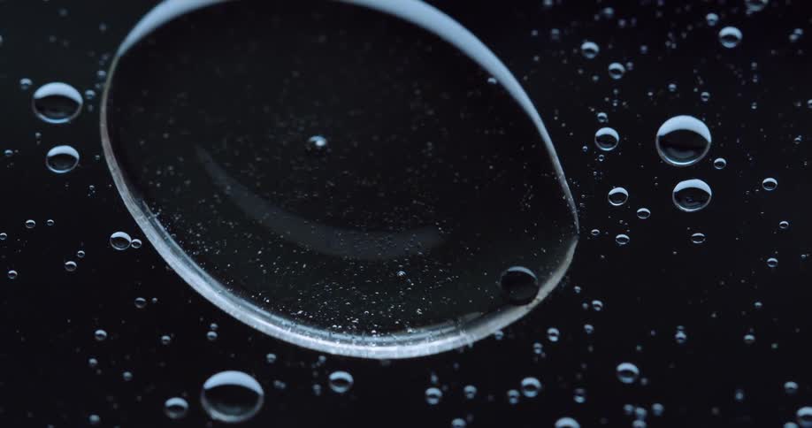 Dense and abstract liquid bubble merging with another and getting larger against a black background