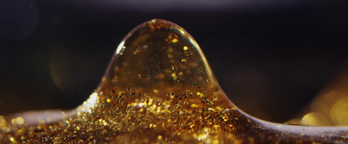 Golden shimmering droplet descending in an abstract manner