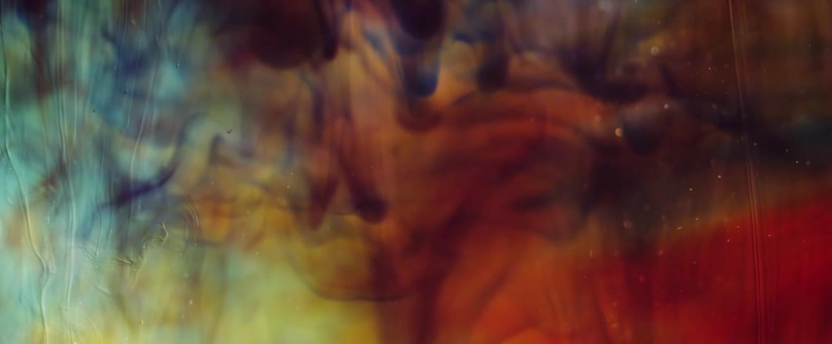 Colorful liquid paint dripping downward slowly around in an abstract way