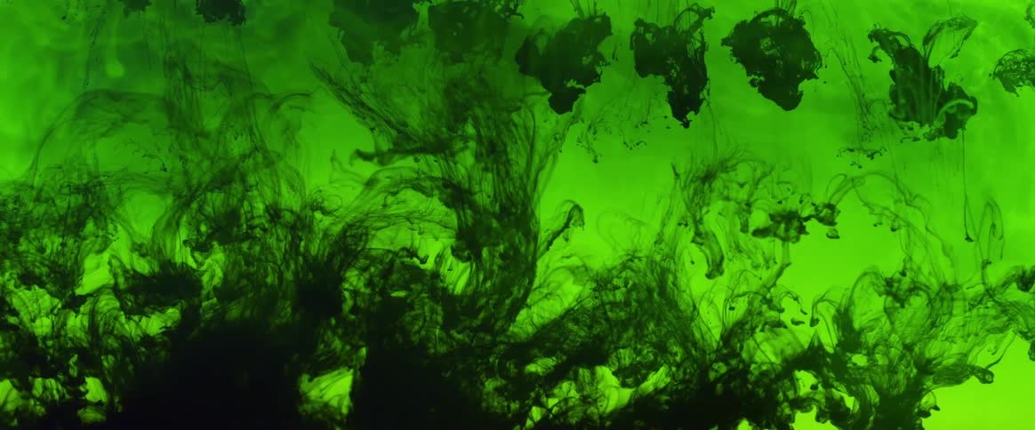 Dark green liquid drops are falling down in lighter green liquid