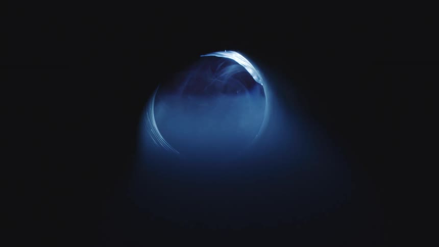 A circle lit up against a black background with smoke rolling across it