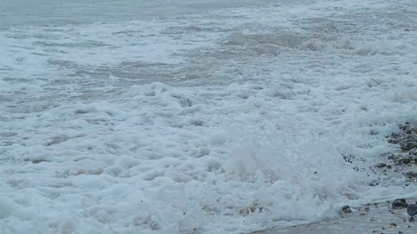 A wave with lots of foam on a beach