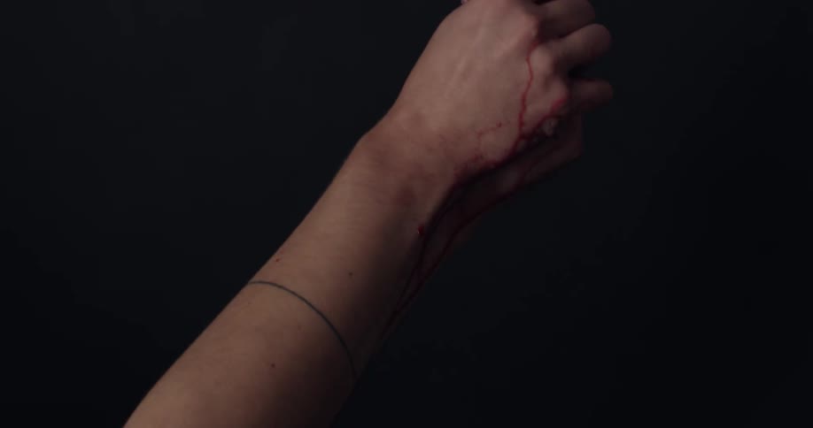 A womans hands squeezing a fruit against a black background