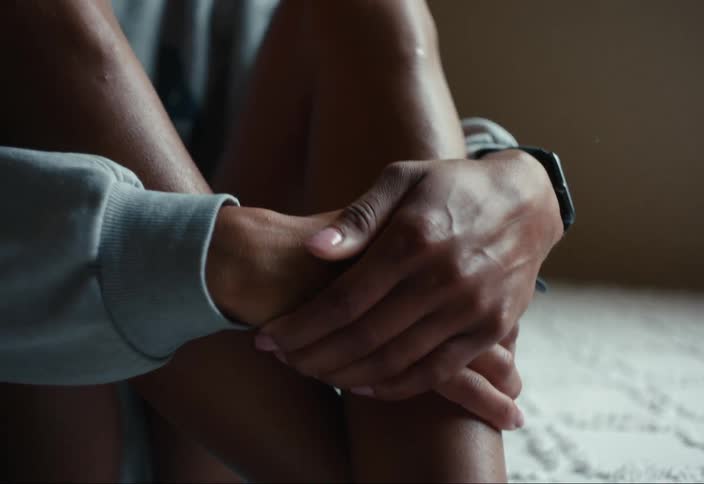 A young woman sitting on a bed and thinking