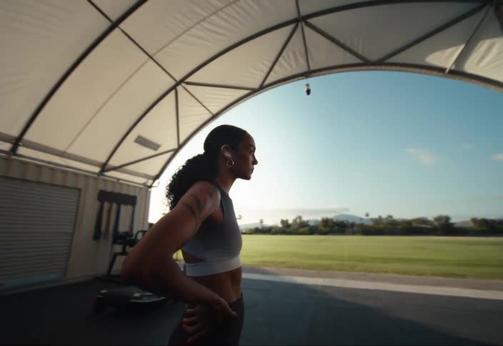 A woman wearing hearing aids stands in an outdoor gym near an american flag