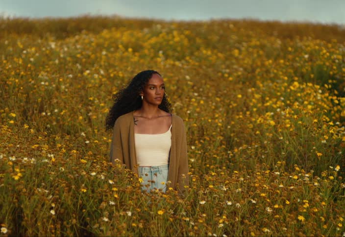 A woman standing in a field of wild flowers and tall grass
