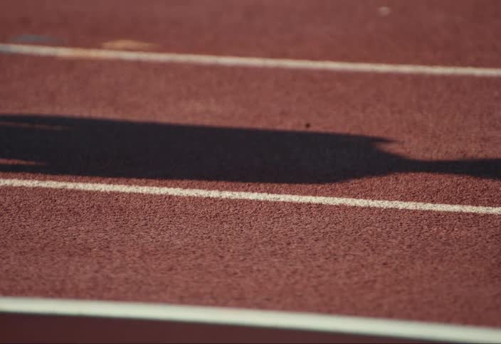 The shadow of a person moves on a track field