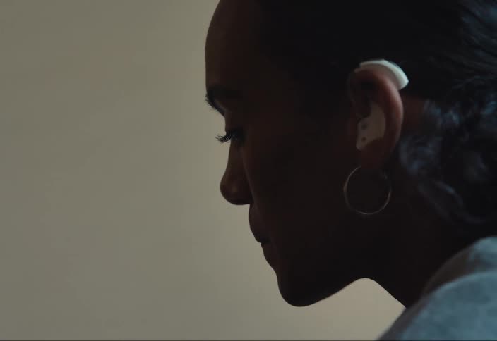 A woman with a hearing aid listening on a phone call