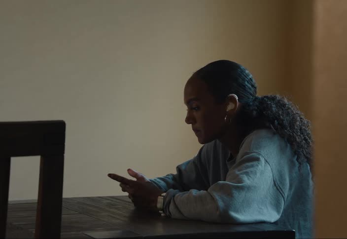Woman sits at table talking on a call