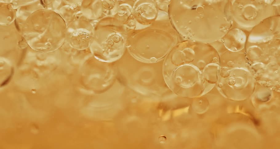 Air bubbles moving on a yellow liquid