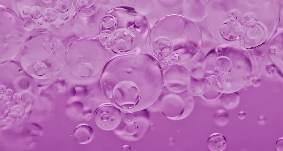 Groups of bubbles floating in purple liquid