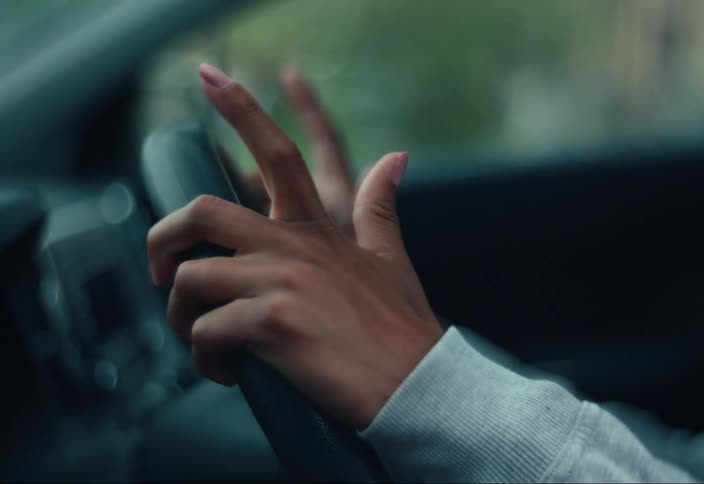 Woman takes her hands off the steering wheel of a car