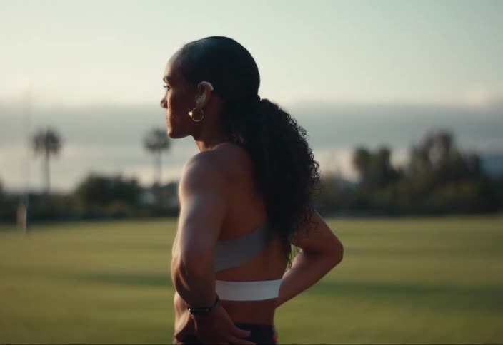 A woman dressed in athletic wear stands in a grassy open field