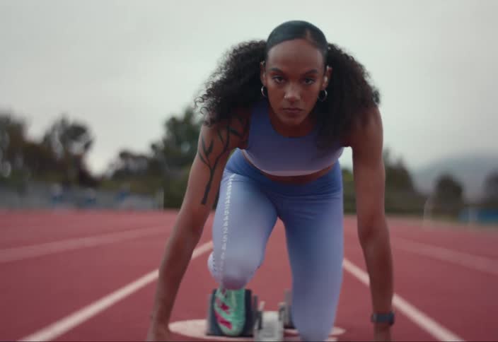 A young woman getting in position on a track to start running