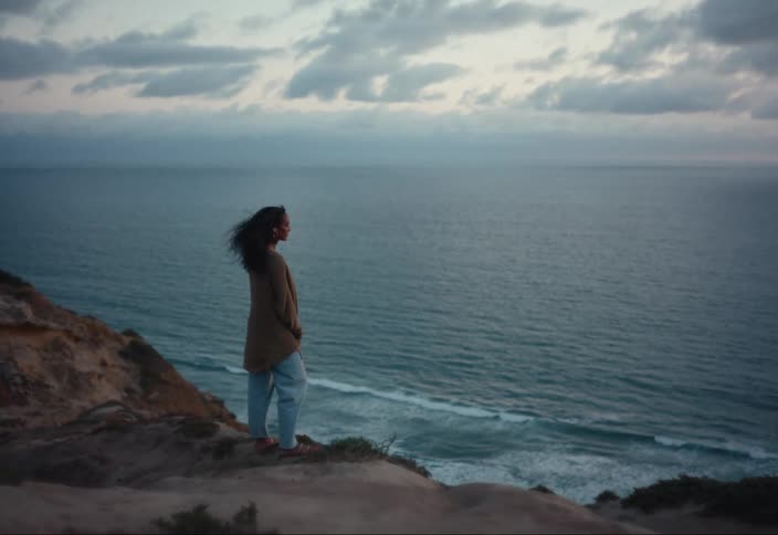 A woman is standing by the shore