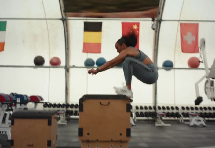 A young woman does box jumps during training session