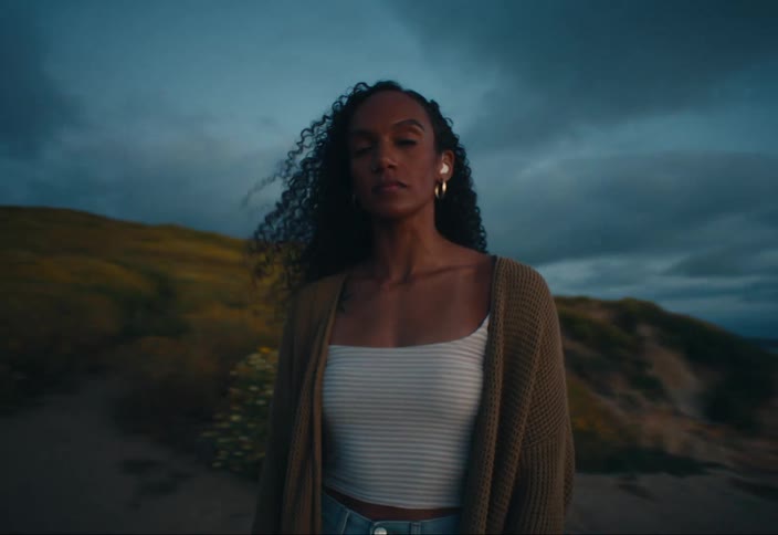 A woman is being orbited around in an area with dark storm clouds looming over her