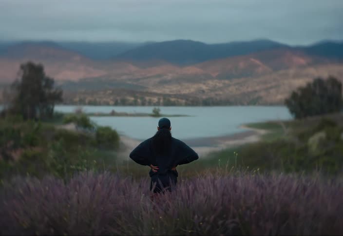 Woman standing in a field of flowers beside a lake