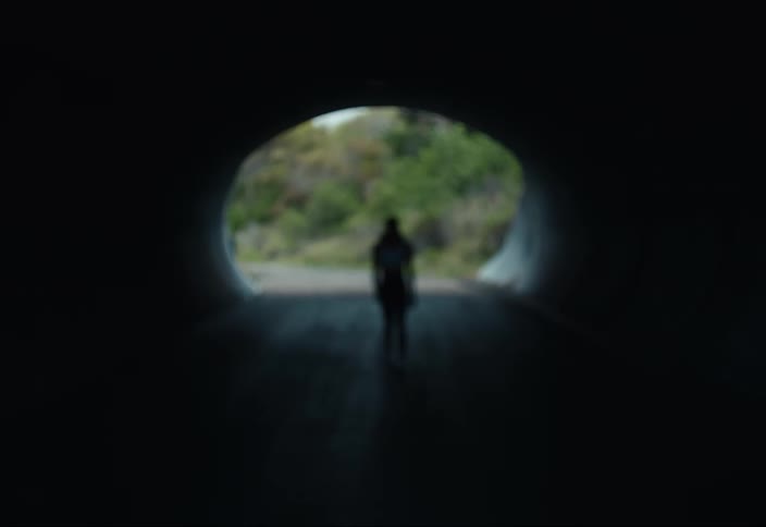 A woman walks through a tunnel