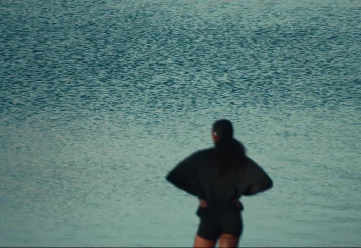 A woman standing outdoors looking out at a lake