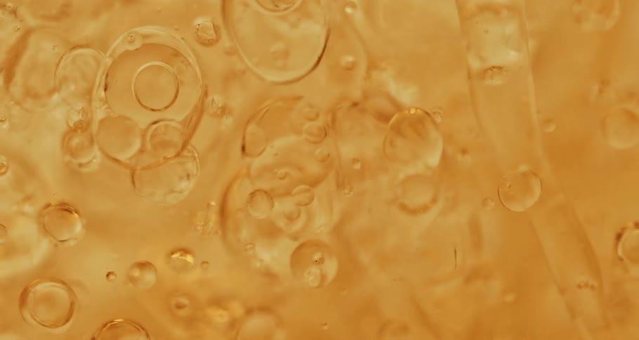 Clear orange oily bubbles moving around in liquid in a glass