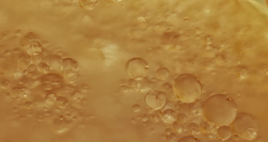 Air bubbles rising on a yellow liquid