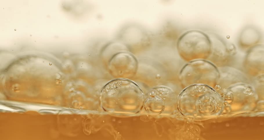 Bubbles fall in slow motion into an orange liquid