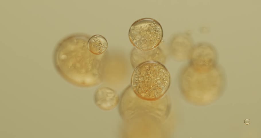 Yellow clear liquid bubble droplets slowly falling down