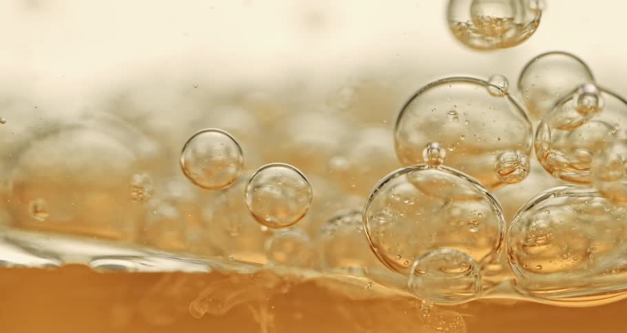 Yellow clear oily bubbles slowly moving downward onto more liquid