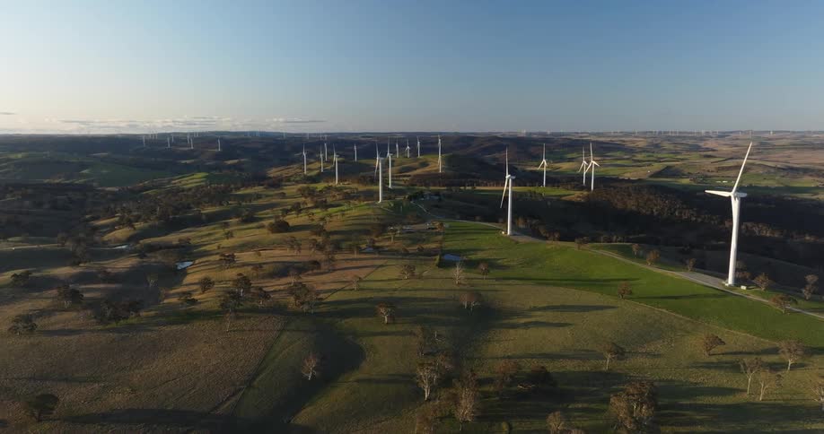 An aerial of a wind farm on grassy land under blue skies