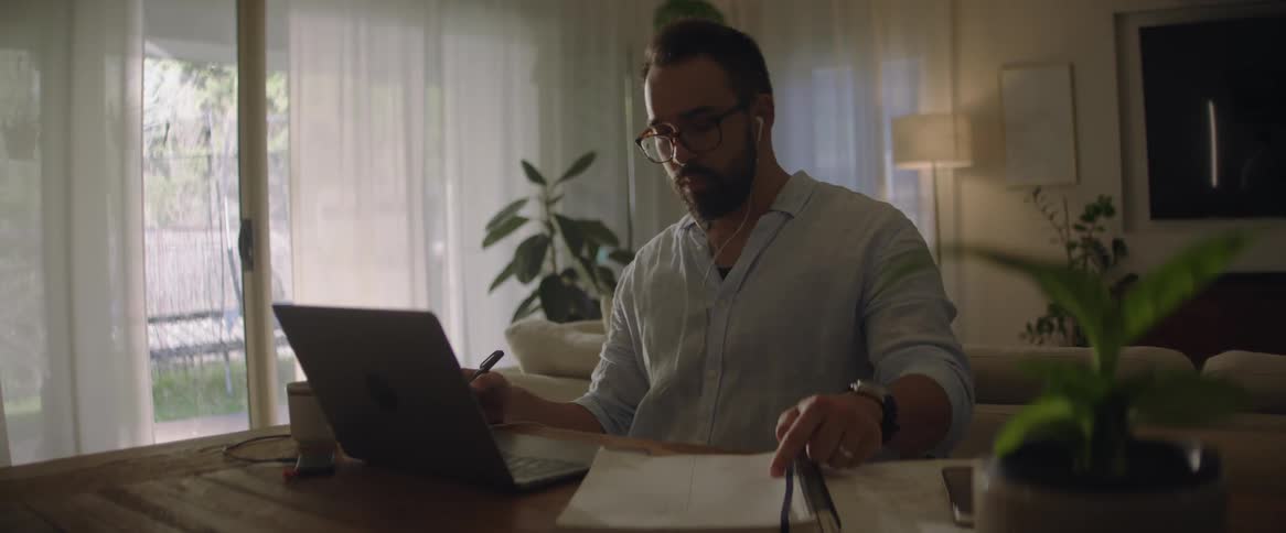 Man working from home talks on a video call through a laptop