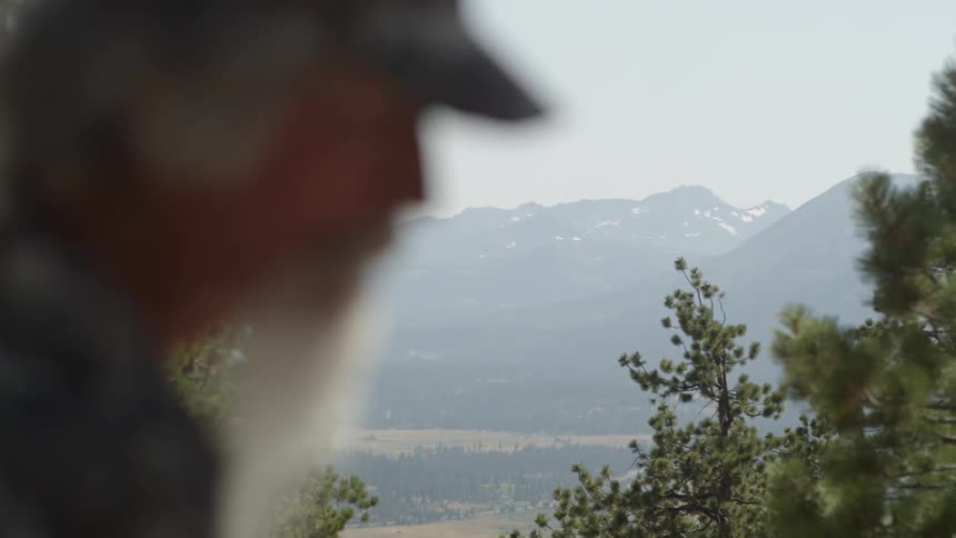 A man is on a tall hill with a valley ahead