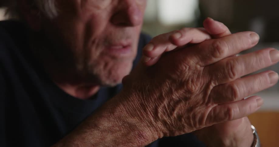 An old man rubbing his hands together